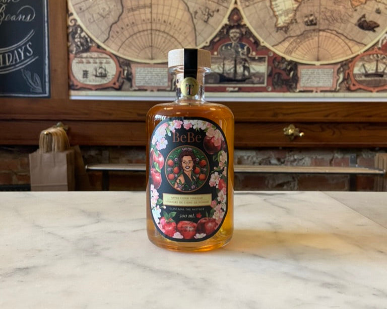 Bottle of apple cider vinegar with decorative label on a marble surface, world map in the background