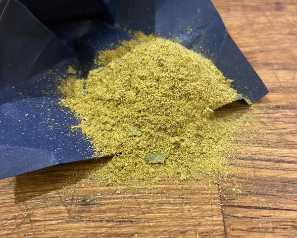 Green Thai curry powder on blue paper and wood.