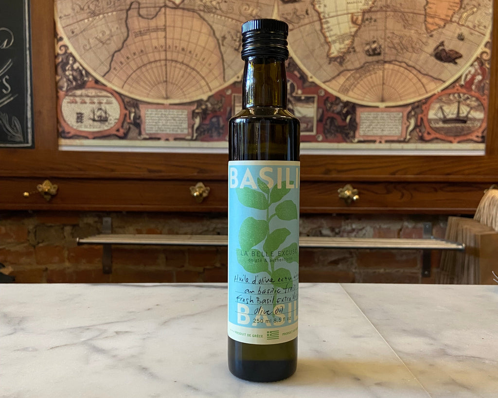 Bottle of basil olive oil with a label on a marble surface, with an old world map in the background.